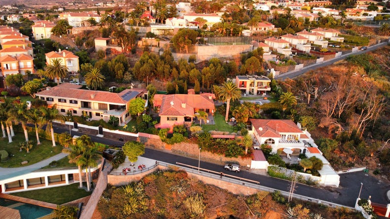 An aerial shot of beautiful mansion homes in Beverly Hills surrounded my palm trees during sunset