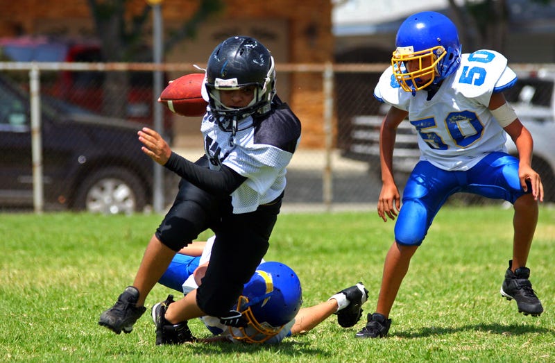 Young american football player running back breaking away from an attempted tackle. All logos and trademarks from uniforms, helmets and cleats have been removed in Photoshop