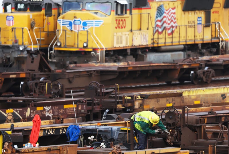 rail worker against backdrop of trains