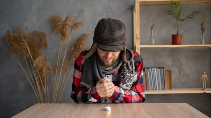 Man whose heating bills are too expensive so he warms himself with a candle. 