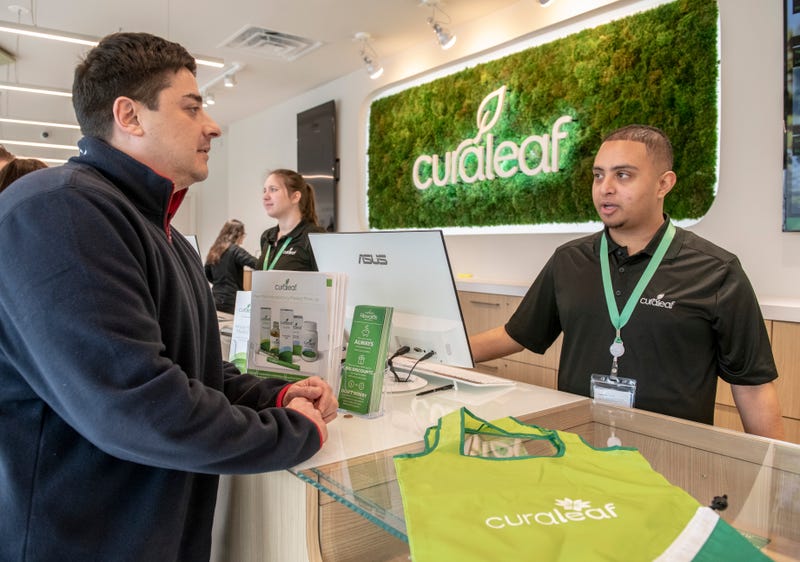 An employee assists a customer during the opening of a Curaleaf medical marijuana dispensary in January 2019.