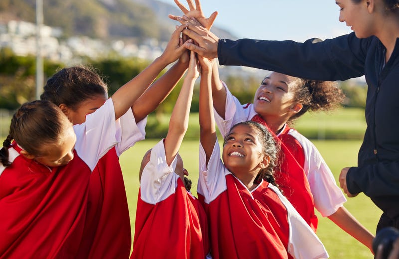 Girls on a team in a huddle raising their arms