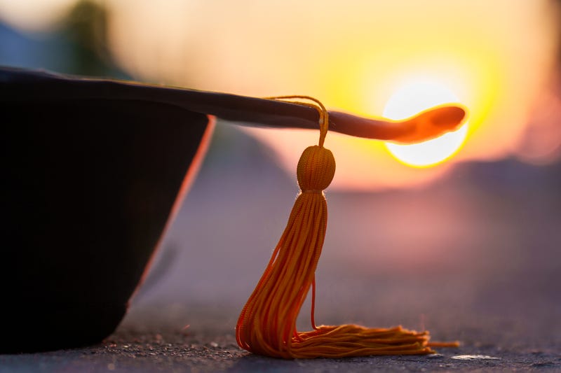 closeup black graduated hat and golden yellow tassels on sunset background