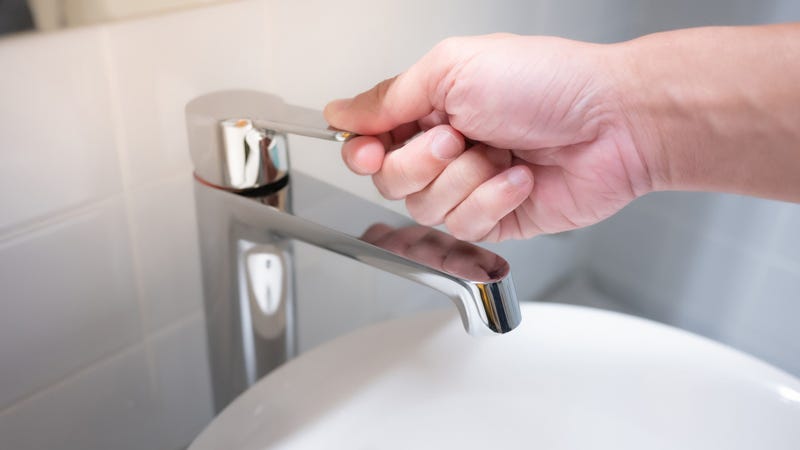 Male hand closing water tap in bathroom - stock photo