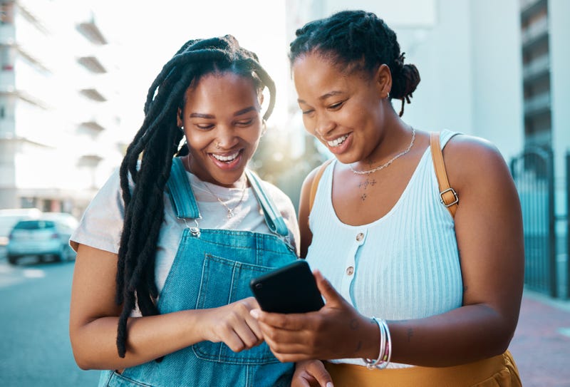 African woman friends with smartphone in urban city reading social media post, check location on digital app or internet search for youth lifestyle. Teenager couple on 5g cellphone chat or networking - stock photo