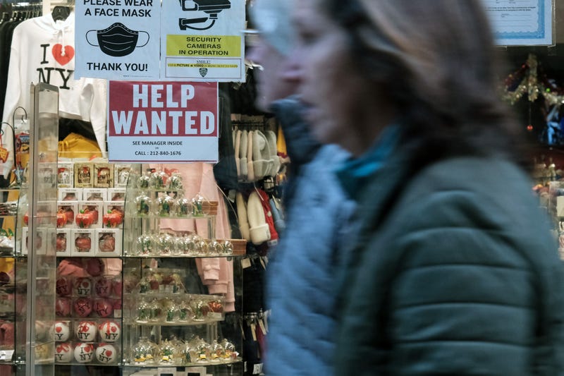 A "help wanted" sign is displayed in a window of a store