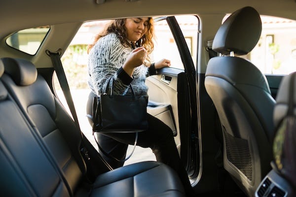 Woman getting into the back of a car