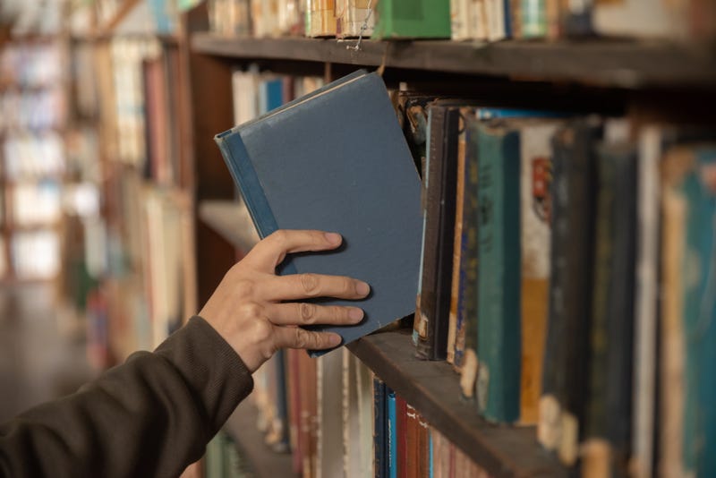 Person grabbing book from shelf 