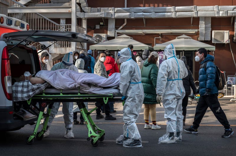 Medical workers wear PPE as they arrive with a patient on a stretcher at a fever clinic on December 9, 2022 in Beijing, China. In a major shift in the country's zero COVID policy, China's government announced Wednesday that people with COVID-19 who have mild or no symptoms will be permitted to quarantine at home instead of at a government facility, are permitted to buy over the counter medications, and will have testing requirements reduced. As part of a 10 point directive, local officials can also no longer lock down entire neighborhoods or cities. (Photo by Kevin Frayer/Getty Images)