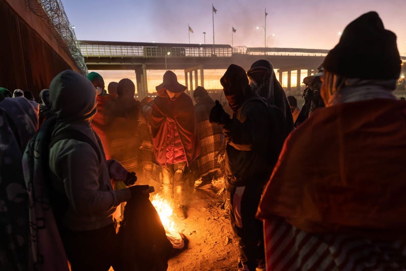Immigrants warm by a fire at dawn after spending a night alongside the U.S.-Mexico border fence on December 22, 2022 in El Paso, Texas. A spike in the number of migrants crossing over to seek asylum in the United States has challenged local, state and federal authorities. The numbers are expected to increase as the fate of the Title 42 authority to expel migrants remains in limbo pending a Supreme Court decision expected after Christmas. (Photo by John Moore/Getty Images)