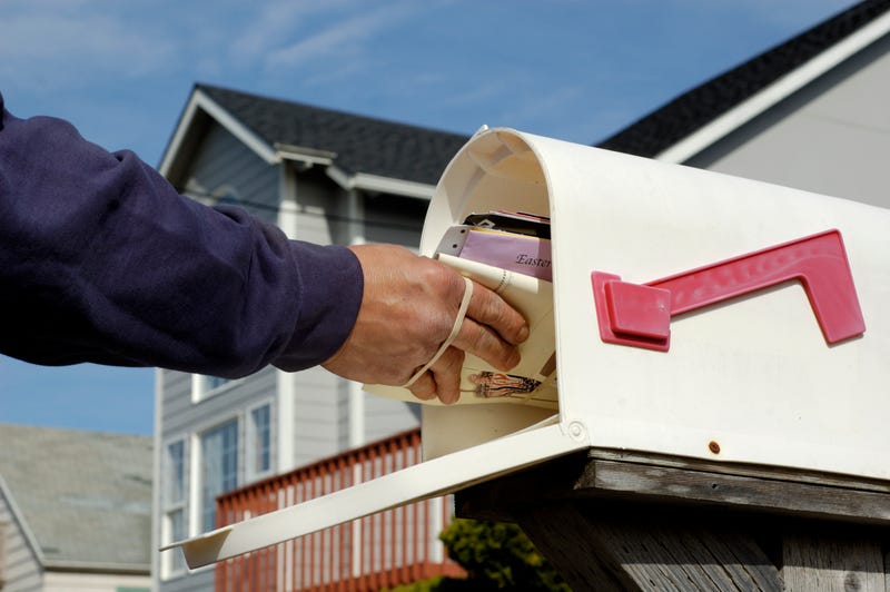 Mailman making a delivery into a mailbox. 