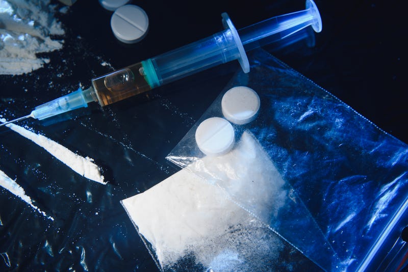 Drugs on a table, including pills and a syringe