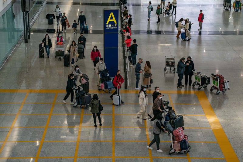 Travelers walk with their luggage at the arrival hall of the Hong Kong International Airport on December 30, 2022 in Hong Kong, China.  