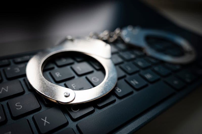 Selective focus on handcuffs on a keyboard cyber crime, hacking, bullying Against law concept in dark low key tone. metal handcuffs on a black keyboard.