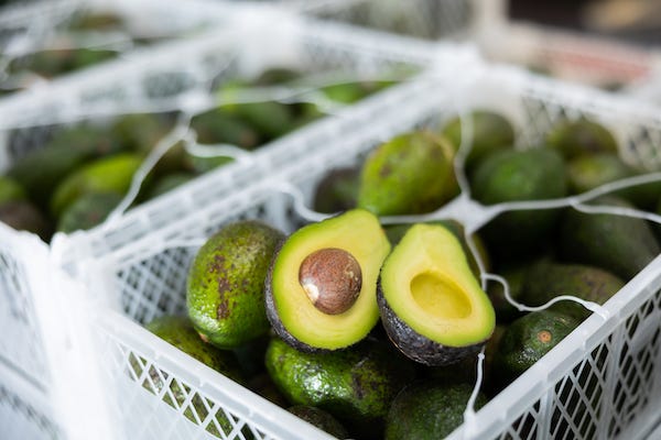 Two halves of ripe hass avocado on box with selected avocado