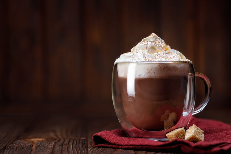 Cocoa or hot chocolate with whipped cream in glass cup on table
