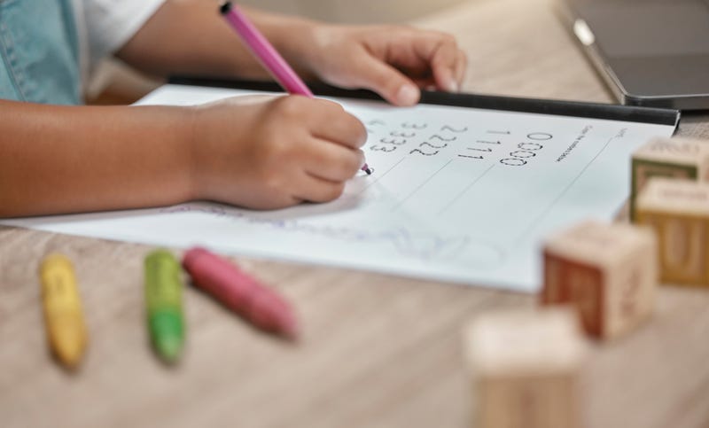 child tracing numbers on a worksheet