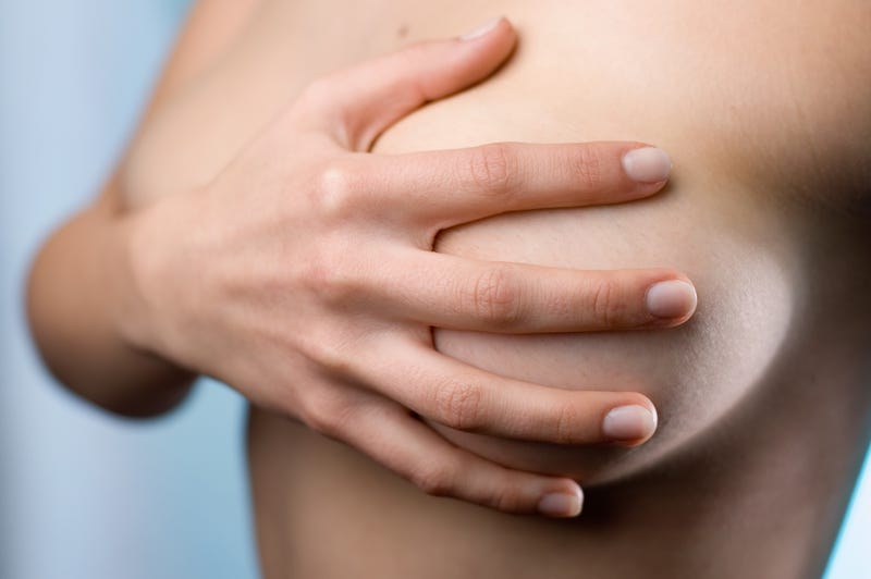 Woman covering her breasts with her hand.