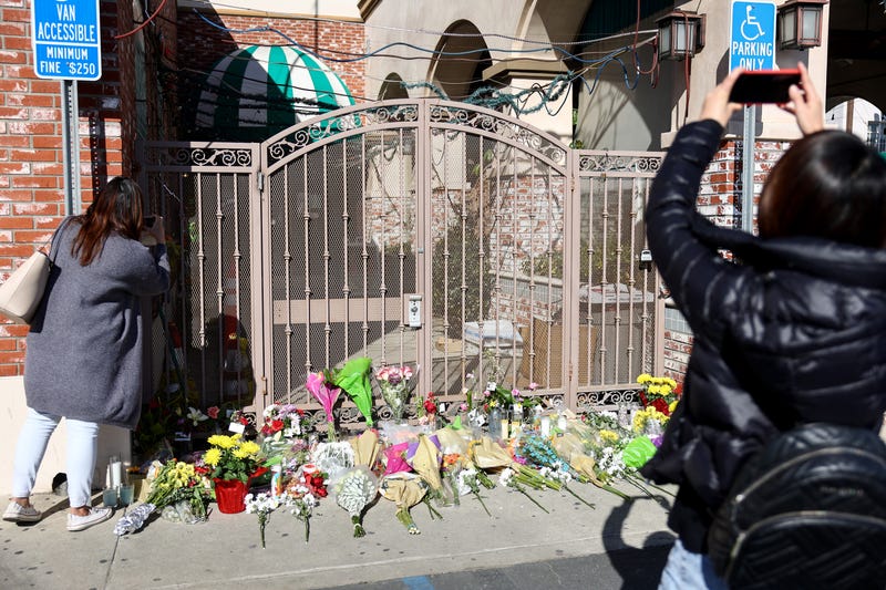 People take photos near a makeshift memorial outside the scene of a deadly mass shooting at a ballroom dance studio on January 23, 2023 in Monterey Park, California. 