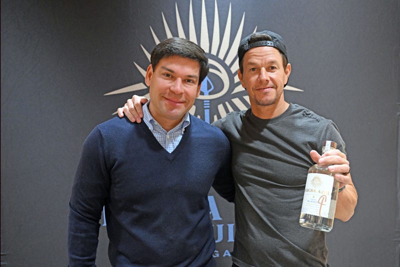 Co-Founder of Flecha Azul Tequila Aron Marquez and Mark Wahlberg pose with bottles of Flecha Azul tequila