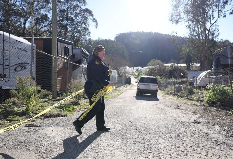 A San Mateo County sheriff deputy pulls police tape across a driveway at a farm where a mass shooting occurred on January 24, 2023 in Half Moon Bay, California.