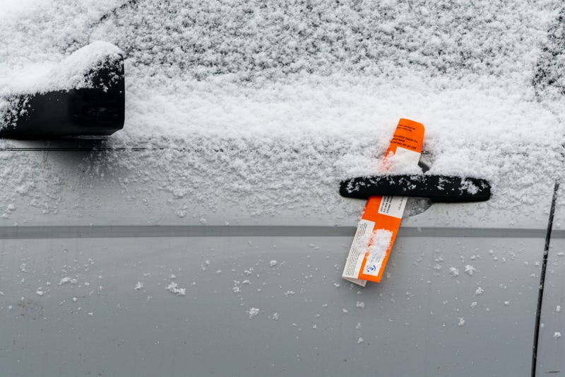 A parking ticket sits inside a car's door handle.