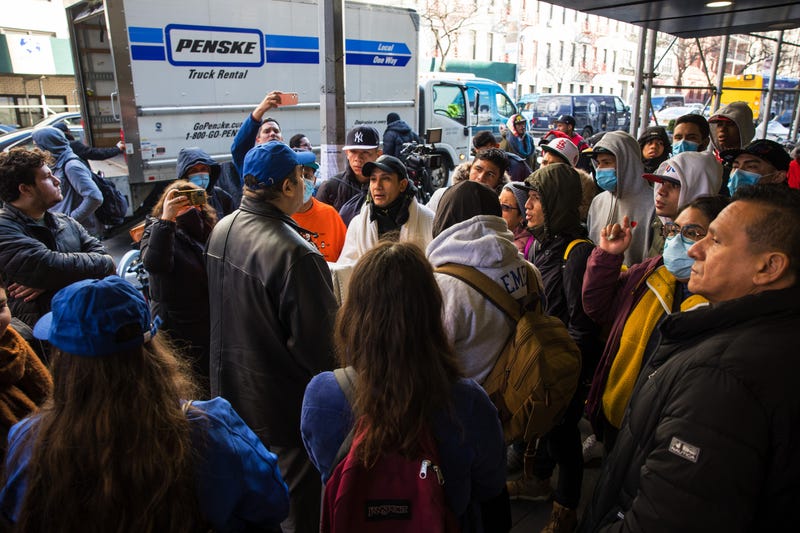 A member of the Mayor's immigration office speaks with migrants who are camping out in front of the Watson Hotel after being evicted on January 30, 2023 in New York City. Migrants who have been staying at the Watson Hotel since arriving to NYC were evicted over the weekend to be relocated to the recently opened up migrant relief center for single adult men at the Brooklyn Cruise Terminal. The ones who refused have been camping out in front of the hotel since eviction. Several migrants who agreed to the relocation returned, complaining of lack of heat and bathroom space.