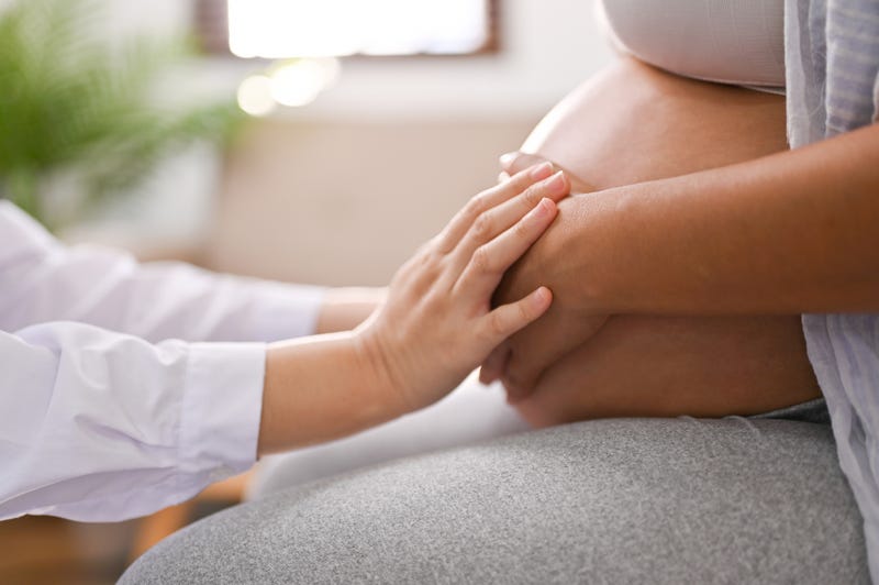 Side view of a doctor touching a pregnant woman's belly.