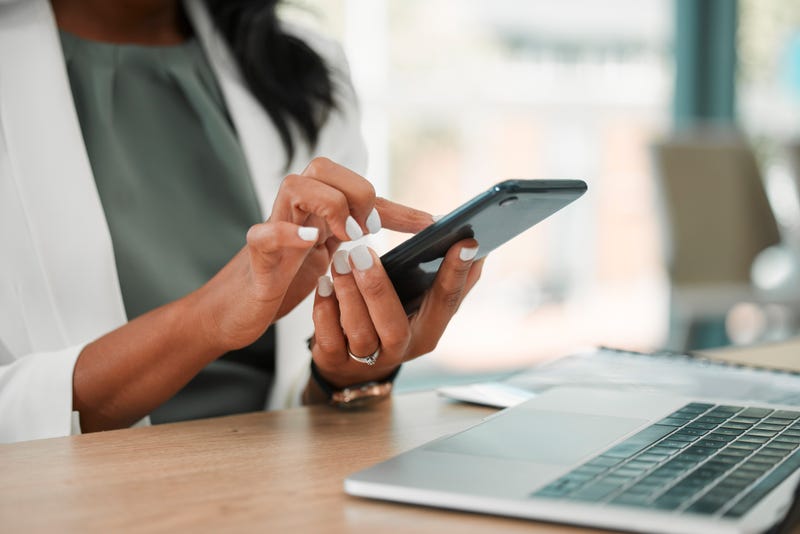 A woman uses a phone and a laptop.