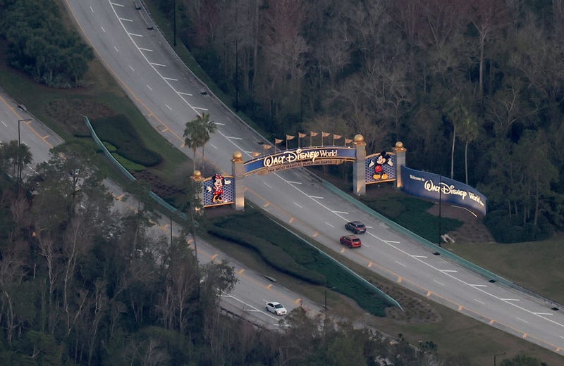 In an aerial view, a Walt Disney World sign hangs over an entranceway to the theme park on February 08, 2023 in Orlando, Florida. As Florida Gov. Ron DeSantis continues his push to punish Walt Disney Co. by taking control of the board of Disney's special taxing district, the company announced today a restructuring. As a result, Disney expects to cut costs by $5.5 billion and lay off roughly 7,000 employees, or about 4 percent of its global workforce. (Photo by Joe Raedle/Getty Images)