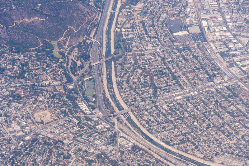 aerial view of highway between mountain and city