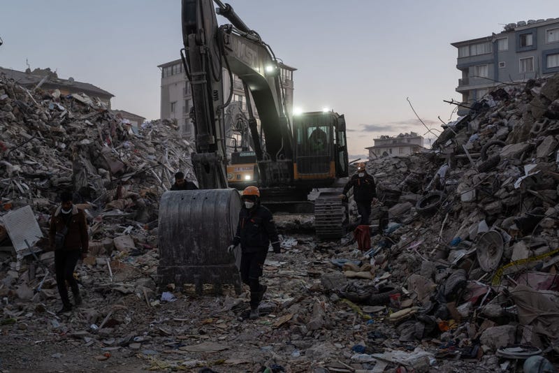 Workers walk past piles of rubble on February 15, 2023 in Hatay, Turkey. A 7.8-magnitude earthquake hit near Gaziantep, Turkey, in the early hours of February 6, followed by another 7.5-magnitude tremor just after midday.
