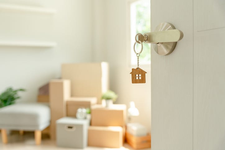Key in a door with a house keychain depicting the housing market. 