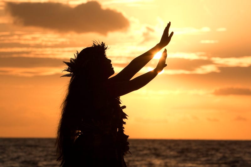 Hawaiian hula dancer performs a hula in front of the tropical sunset.