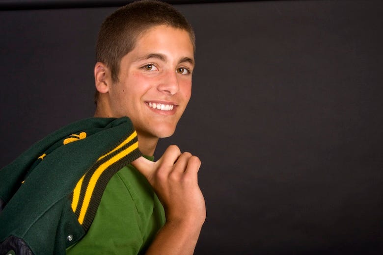 Man posing with letterman jacket slung over shoulder