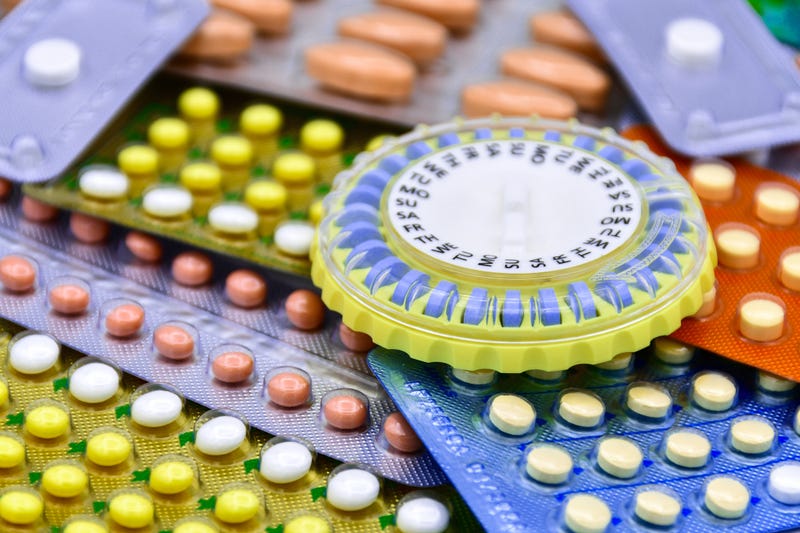 Oral contraceptive pill on pharmacy counter with colorful pills strips background.