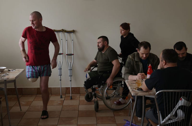 Ukrainian soldiers who have lost limbs while fighting against the Russians in eastern Ukraine, including Ivan Nekrasov (C), 35, who drove a Gvozdika self-propelled howitzer and lost both legs when it hit a landmine, arrive for lunch at the cafeteria at the rehabilitation center that is their home for now on February 25, 2023 in Lviv, Ukraine.