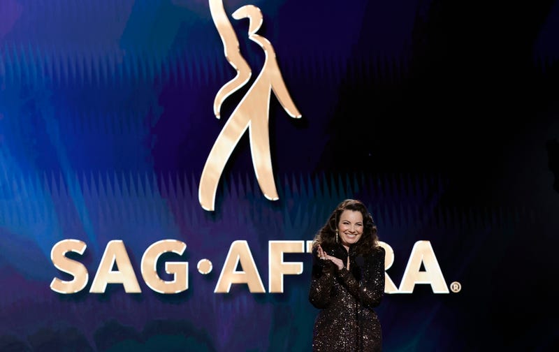fran drescher onstage in front of a backdrop with the sag-aftra logo
