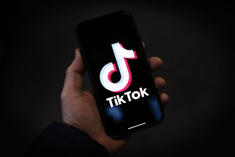 A TikTok logo is displayed on an iPhone