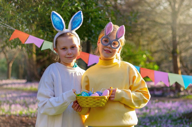Little girls with rabbit ears hold basket with colorful eggs. Easter bunny costume. Celebration, party, decorating. - stock photo