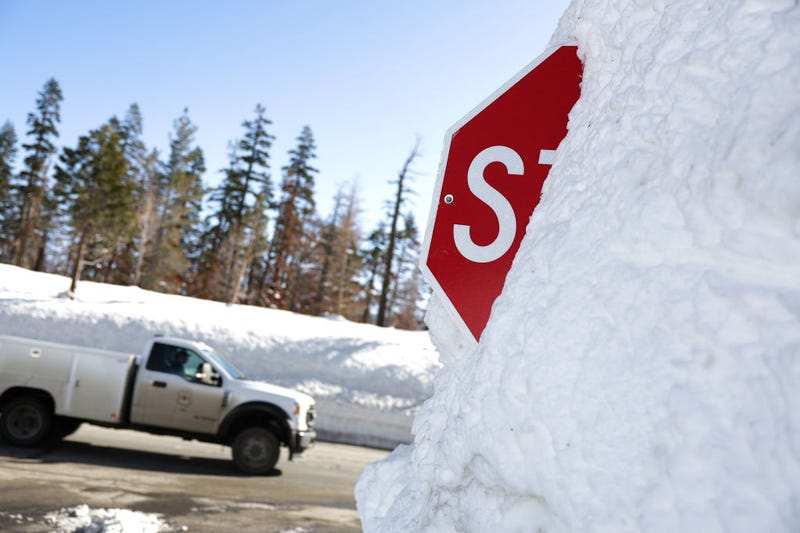 A truck passes by a stop sign that is buried in snow on March 03, 2023 in Twin Bridges, California.