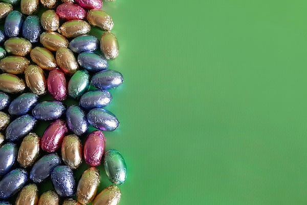 Mini chocolate eggs in front of a green background