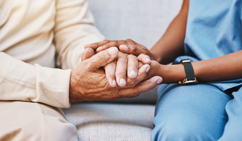 Home care nurse holds senior patient's hand