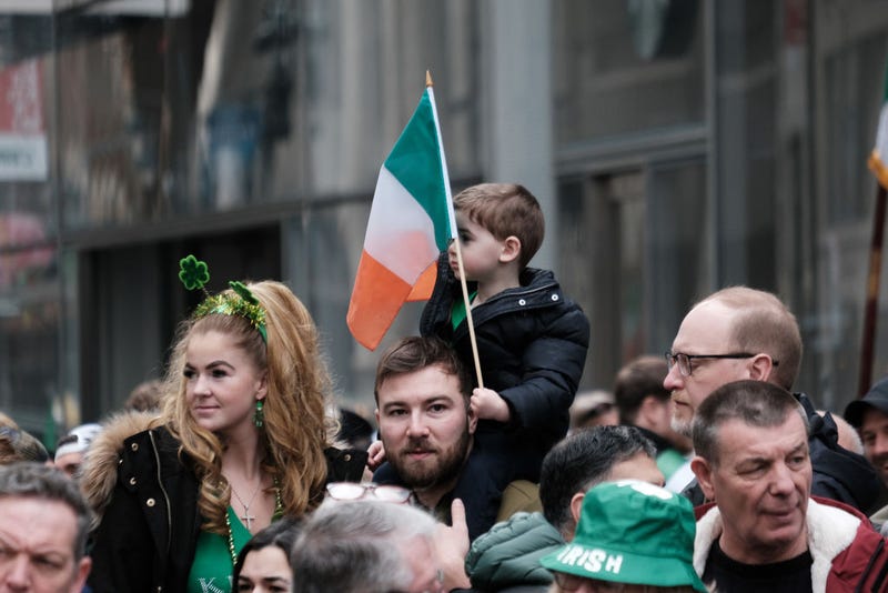 A child holds an Irish flag while watching the St. Patrick's Day Parade