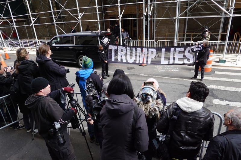Demonstrators hold a banner in front a group of journalists outside of the Criminal Courts Building on March 22, 2023 in New York City.