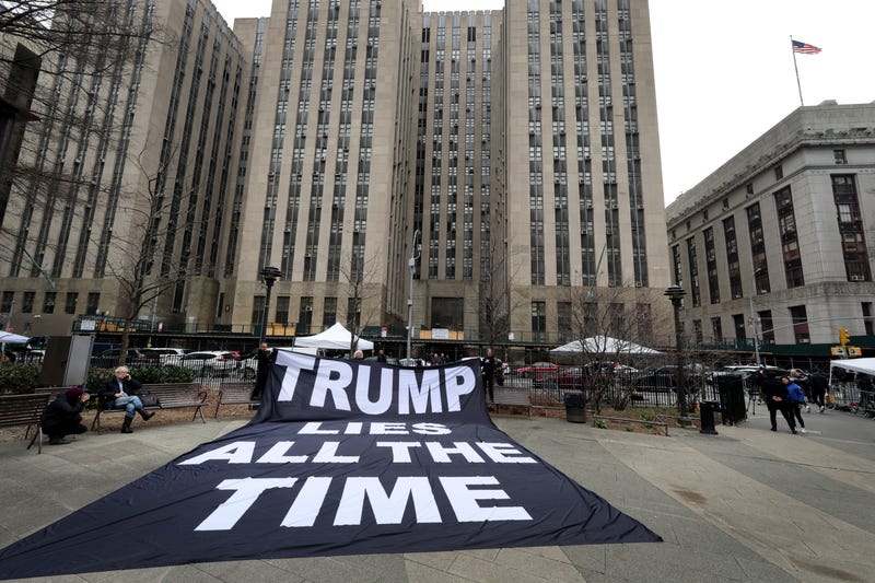 Demonstrators unfurl a banner near Manhattan Criminal Court on March 23, 2023