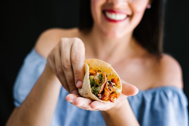 Woman smiling holding a taco