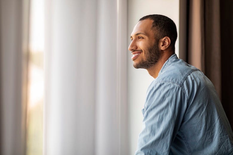 Smiling man starting out of the window at his home