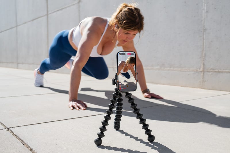 A woman films herself doing an exercise.