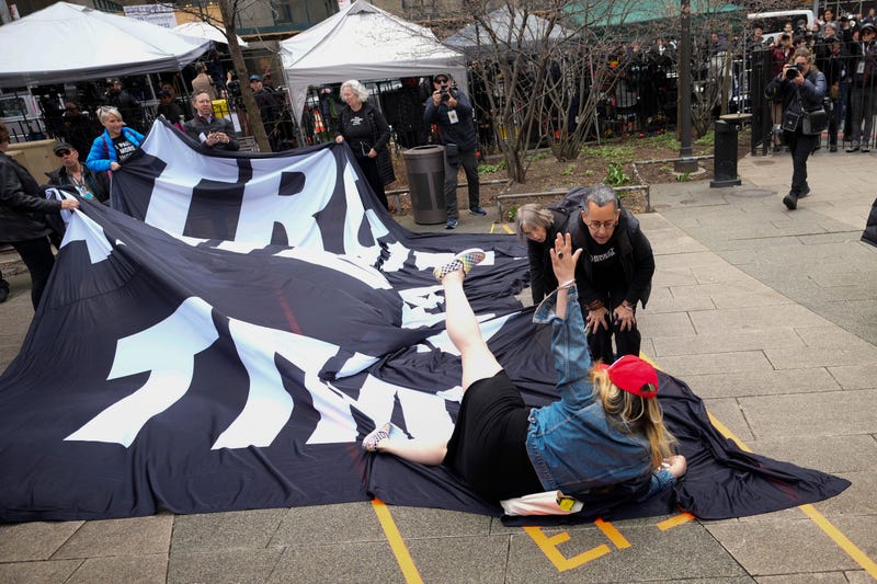 A supporter of Donald Trump tumbles to the ground on top of a banner criticizing him outside the courthouse where Trump will arrive later in the day for his arraignment on April 4, 2023